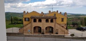 une grande maison jaune avec une clôture devant elle dans l'établissement Agriturismo San Michele, à Cossignano