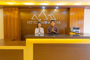 un hombre y una mujer parados detrás de un mostrador en Hotel Snow Peak, en Pokhara
