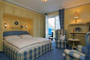 a bedroom with a large bed and two chairs at Hotel Wiesbaden in Wenningstedt