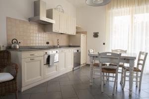 アルベンガにあるLuisella Apartmentsの白いキャビネット、テーブルと椅子付きのキッチンが備わります。