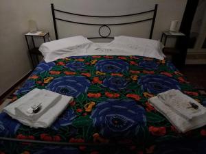 Una cama con colcha floral y toallas. en B&B En Suite, en Matera