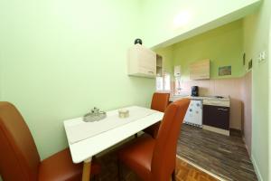Il comprend une petite cuisine avec une table blanche et des chaises orange. dans l'établissement VILLA TERRACOTTA APP 4, à Starigrad-Paklenica