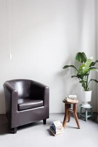 a black leather chair in a living room with a plant at Charming flat Righi Bologna in Bologna