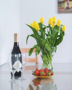 een glazen vaas met gele tulpen en een fles wijn bij Zbawiciela Square P&O Serviced Apartments in Warschau
