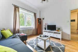 een woonkamer met een blauwe bank en een tv bij Zbawiciela Square P&O Serviced Apartments in Warschau