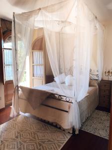 1 dormitorio con cama con dosel y cortinas blancas en Finca Galea, en Carballido