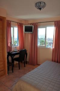 a bedroom with a bed and a desk with a computer at Hotel Mayarí in Calabardina