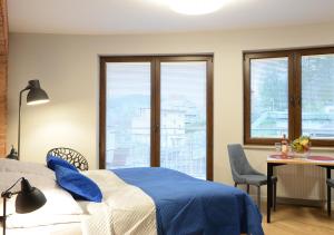 a bedroom with a blue bed and a table and windows at Apartamenty Gaja in Krynica Zdrój