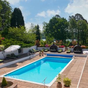 una piscina en un patio con sillas y sombrilla en Champneys Forest Mere, en Liphook