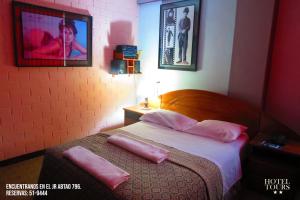 a bedroom with a bed with two pink pillows on it at Hotel Tours in Huánuco