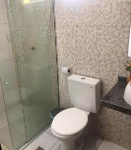 a bathroom with a toilet and a glass shower at Recanto Caiçara Pousada in São Miguel dos Milagres