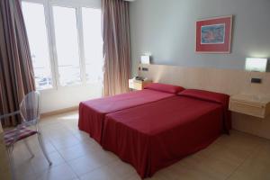 a hotel room with a red bed and a window at Hotel Adiafa in Barbate