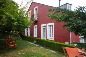 un edificio rosso con un cortile con sedie e alberi di CASA PELTRE a Sarria