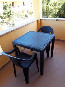 - Balcón con mesa azul y 2 sillas en S'Apposentu ( La Camera), en Villasimius