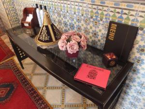 una mesa de cristal con un libro y flores. en Riad Mouna en Marrakech