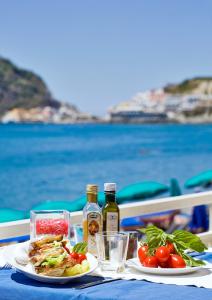 uma mesa com dois pratos de comida e garrafas de vinho em Hotel Vittorio Beach Resort em Ischia
