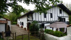 a white and black house with an umbrella at Maison d'hôtes de charme ttakoinenborda in Sare