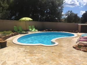 einen Pool mit Stühlen und einem Sonnenschirm in der Unterkunft Apartments Vila Moli in Bibinje