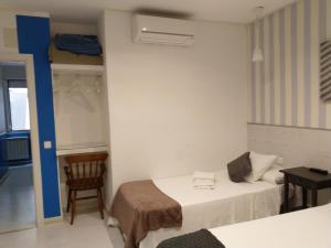 a small room with two beds and a chair at Hostal Mendoza in Madrid