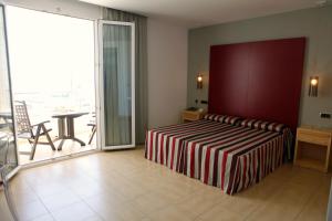 a bedroom with a bed and a balcony with a table at Hotel Adiafa in Barbate