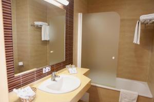 a bathroom with a sink and a mirror and a tub at Hotel Adiafa in Barbate