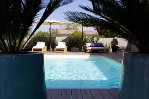 a swimming pool with two chairs and an umbrella at La cabane 62 in La Teste-de-Buch