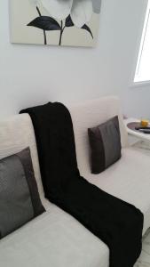 Un sofá blanco con almohadas negras. en BEAUTIFUL SMALL APARTAMENT en Costa Calma