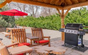 a grill and two chairs and a table with an umbrella at Hotchkiss Inn Motel in Hotchkiss