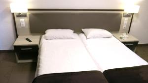 two twin beds in a hotel room with two tables at Appart'hotel le Pèlerin in Lourdes