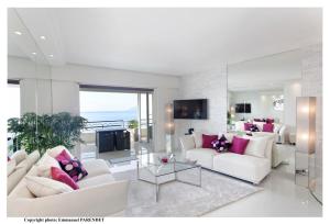 a living room with white furniture and pink pillows at Beautiful modern apartment in La Croisette with sea view in Cannes