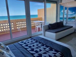 a room with a bed and a couch and windows at Barcaresa-RAVISSANT APPARTEMENT PISCINE VUE MER WIFI PARKING GRATUIT in Le Barcarès