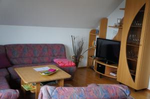 sala de estar con sofá, mesa y TV en Ferienwohnung Bleialf, en Bleialf