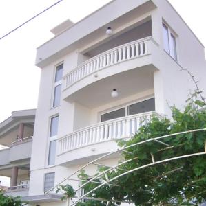 a white building with a balcony on the side of it at DK Apartmani in Dobra Voda