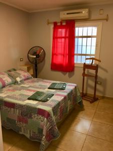 sypialnia z łóżkiem i oknem z czerwoną zasłoną w obiekcie Casa con Garage Puerto Iguazú, zona residencial w mieście Puerto Iguazú