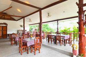 a dining room with tables and chairs and windows at Krathom Khaolak Resort in Khao Lak