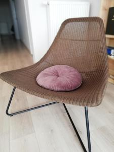 einen Rattanstuhl mit einem rosa Kissen darauf in der Unterkunft appartement oostende vlak bij zee in Ostende