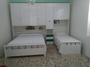 a bedroom with two beds and white cabinets at Case Vacanze Tra Mare e Monti "Da Nora" in Crucoli