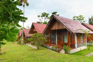a wooden house with a red roof in a yard at Krathom Khaolak Resort in Khao Lak