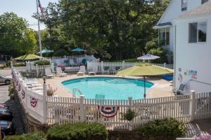 a white fence around a swimming pool with an umbrella at Sea View Motel in Ogunquit