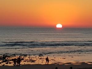a group of people standing on the beach at sunset at Residencial La Teja in Zahora