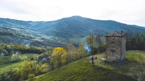 a stone tower on a hill with mountains in the background at Tower house Gombola in Polinago