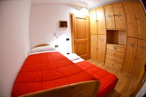 sypialnia z czerwonym łóżkiem i drewnianą szafką w obiekcie RESIDENZA GENZIANA w mieście Passo del Tonale