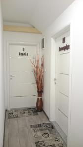 a hallway with two doors and a vase on the floor at Guest House Villa Herbarium in Slavonski Brod