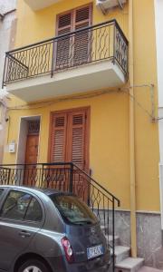a car parked in front of a yellow building with a balcony at Casa Vacanza Di Maggio in Cinisi