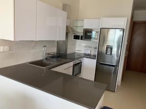 cocina con armarios blancos y nevera de acero inoxidable en WATERFRONT FLAT en Sere Kunda NDing