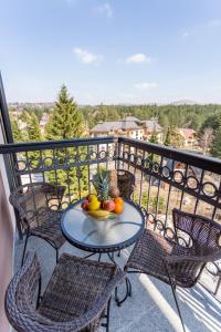 a table with a bowl of fruit on a balcony at Delights Apartment Zlatibor in Zlatibor