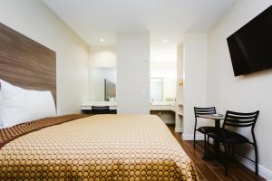 1 dormitorio con 1 cama, escritorio y sillas en scottish inn & suites, en Baytown