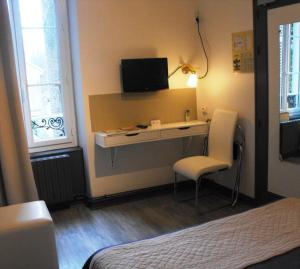 a bedroom with a desk with a tv and a chair at Hôtel Restaurant Les Capucins - Repas Possible in Avallon