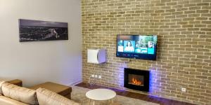 uma sala de estar com lareira e uma televisão numa parede de tijolos em Appart'HomeCity - Rouen Grand Voile em Rouen