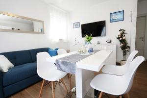 a living room with a blue couch and a white table and chairs at Apartments Romarin in Supetar